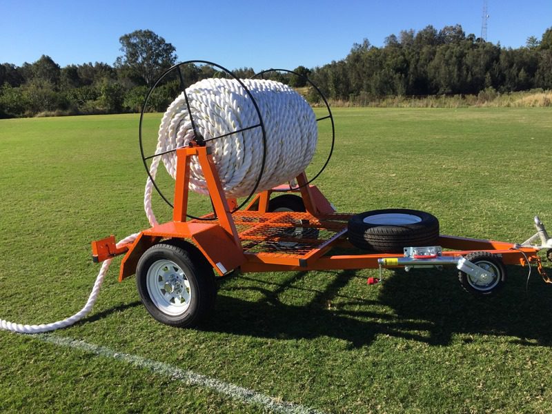 Phto of our Boundary Rope Trailer. It is orange in colour with a very heave white rope. Tt has a tow bar and is towed around the boundary by our ride on mower.