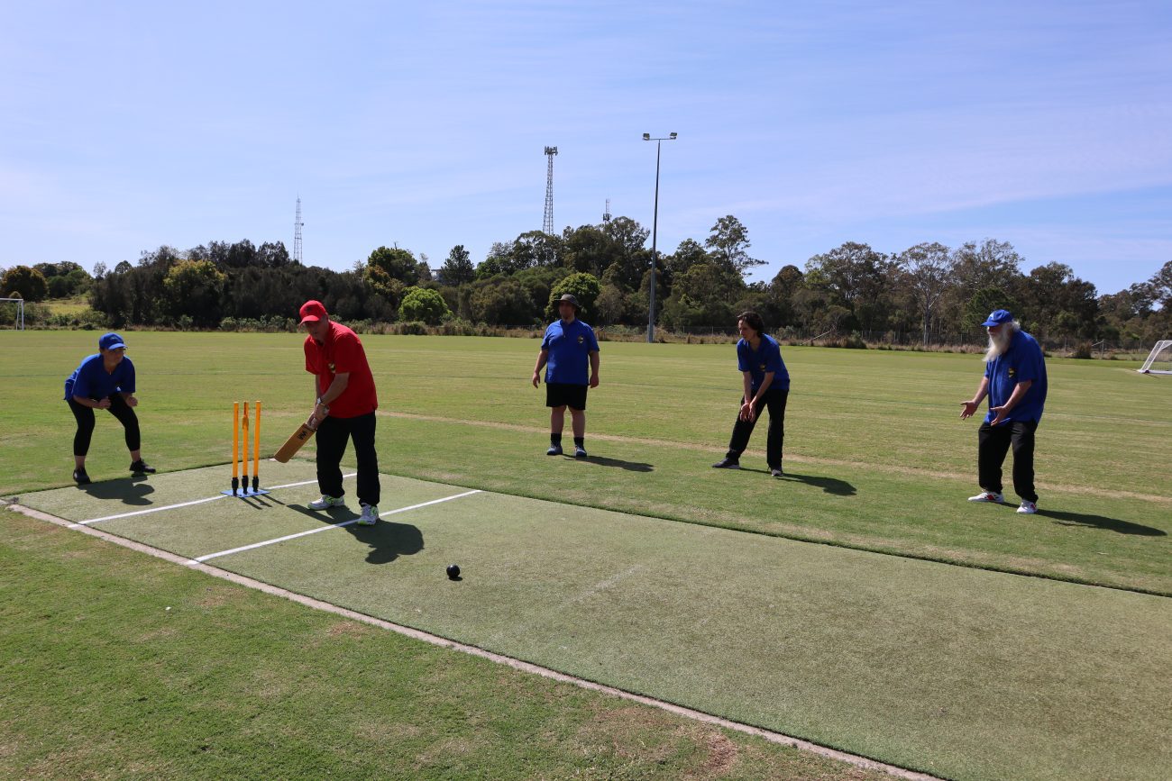 Paul, Captain of the Red Dragons team is about to wack the new beeping ball to the boundary. At wicketkeeper, Julie and her fellow fielders are doing their best to stop the ball.