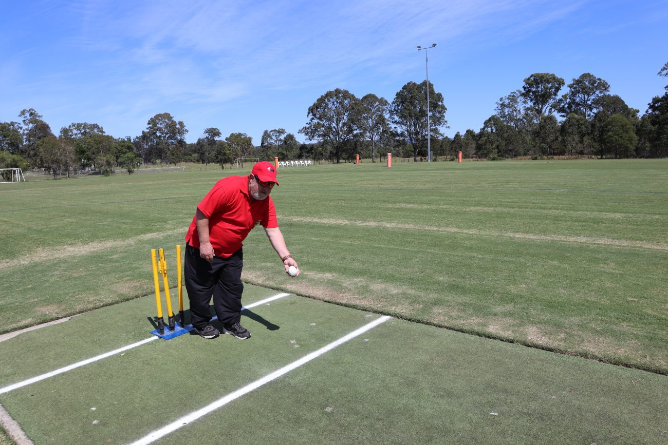 Johnny from the Red Dragons team bowling the new white beeping cricket ball. This picture shows Johnny dressed in the Red Dragons uniform with the white ball in hand just before it was bowled.